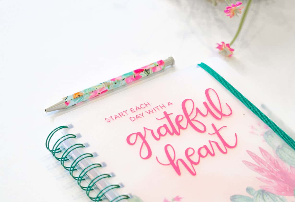 1grateful heart journal and floral pen on a white