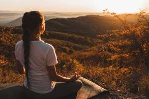 Woman meditating alone on hill with amazing autumn mountain view